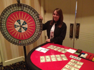 One of our professional and friendly casino dealers posing next to our beautiful money wheel.