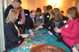 A crowded roulette table with players reaching to place their bets.